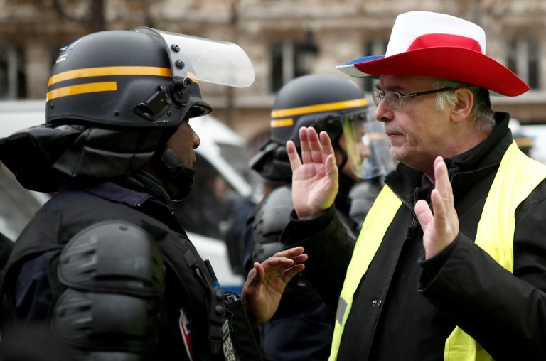 A protester wearing yellow vest, a symbol of a French drivers' protest against higher fuel prices, talks to the police officer on the Champs-Elysee in Paris, France, November 24, 2018. REUTERS/Benoit Tessier