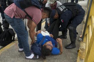 A woman faints after walking for several days from Honduras on the crowded border bridge separating Guatemala and Mexico