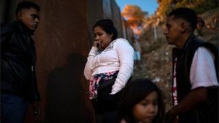 Migrants from Honduras stand by the border fence in Tijuana, Mexico on 2 December, 2018