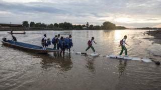 School kids and others disembark from small canoes